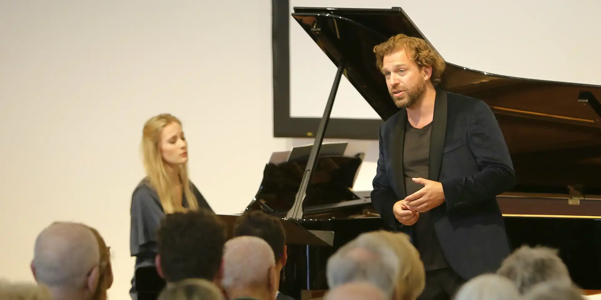 Eine Pianistin an einem Flügel während eines Konzerts mit Besuchern